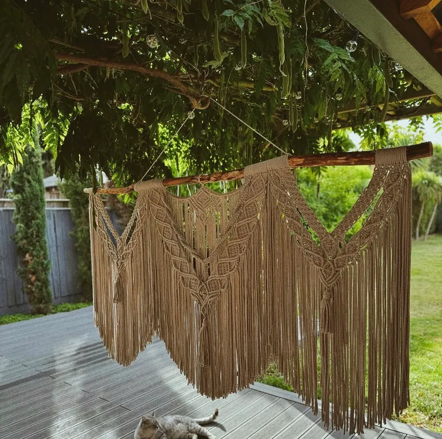 A large macrame hanging under outdoor greenery