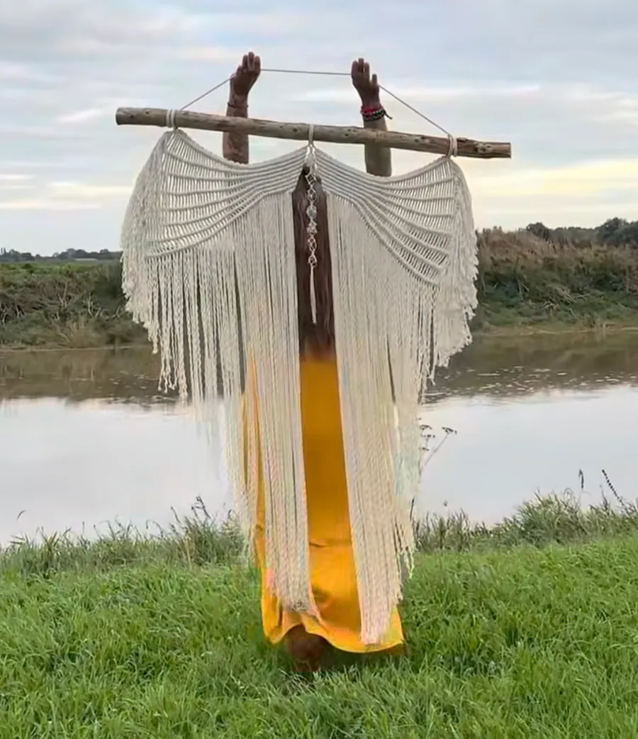 A macrame wing hanging held outdoors by the water