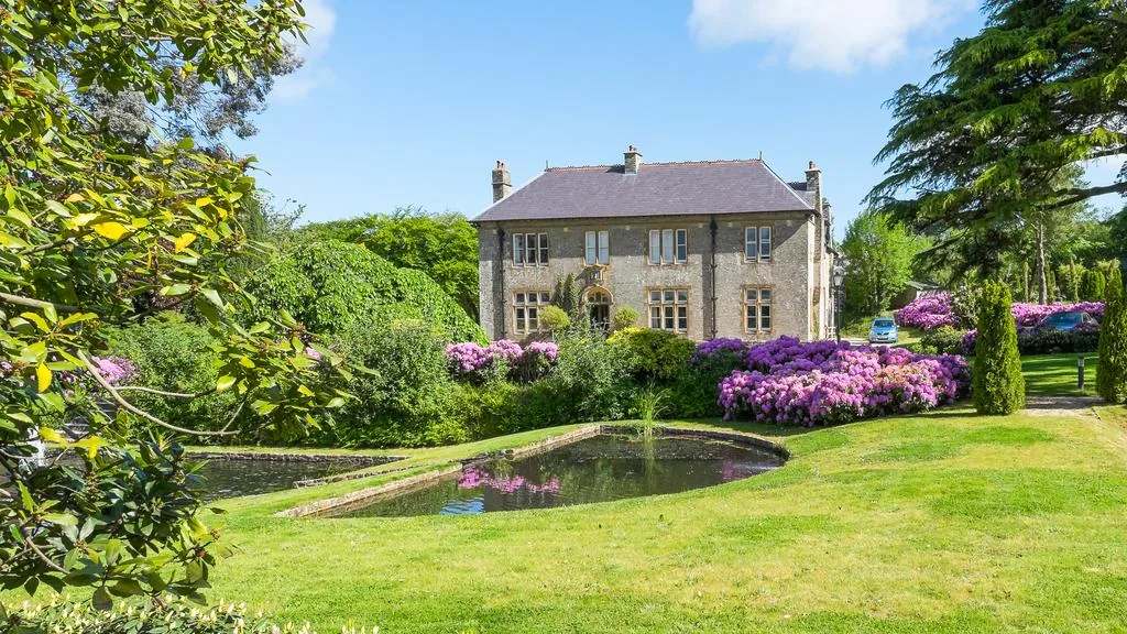 Kentisbury Grange manor house with rhododendrons and ornamental pond